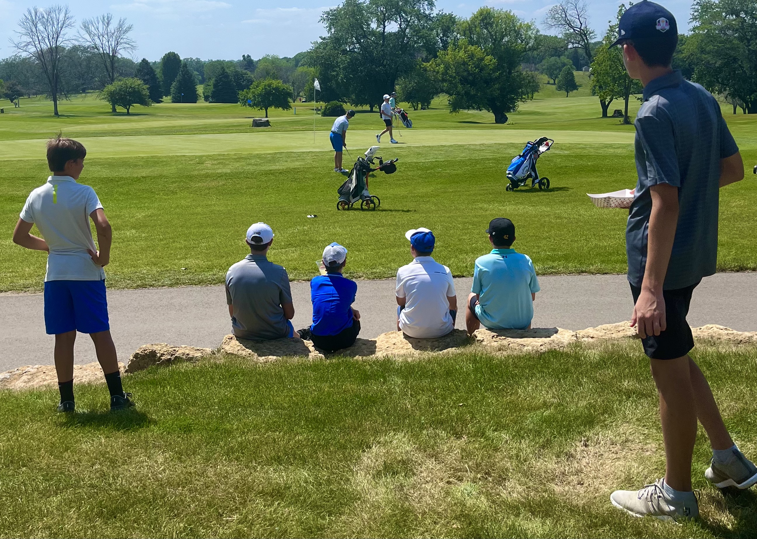 Boys 12-13 division watching the final group on the green